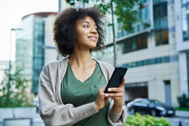 A woman holding her phone on a city street